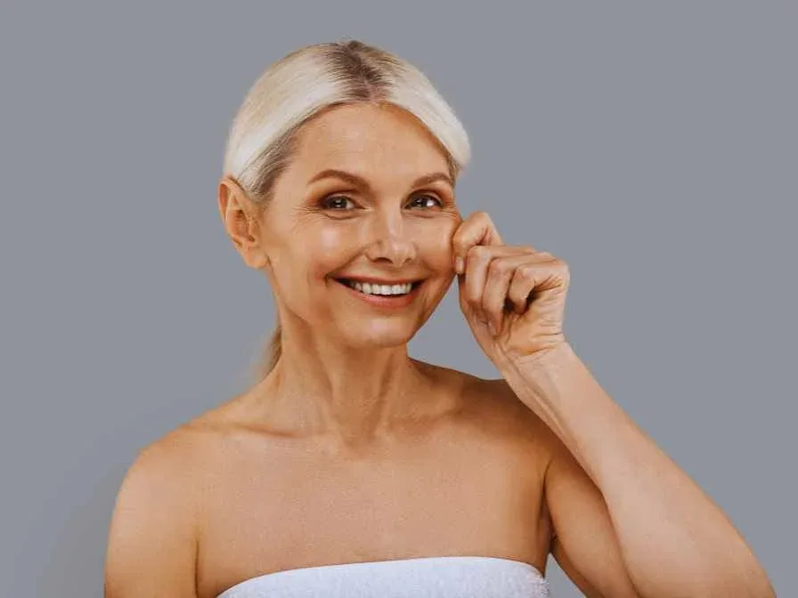 Une femme satisfaite de son massage du visage Kobido, qui a une peau rajeunit et raffermit