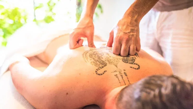 Une personne reçoit un massage avec un tatouage de tigres sur le dos.