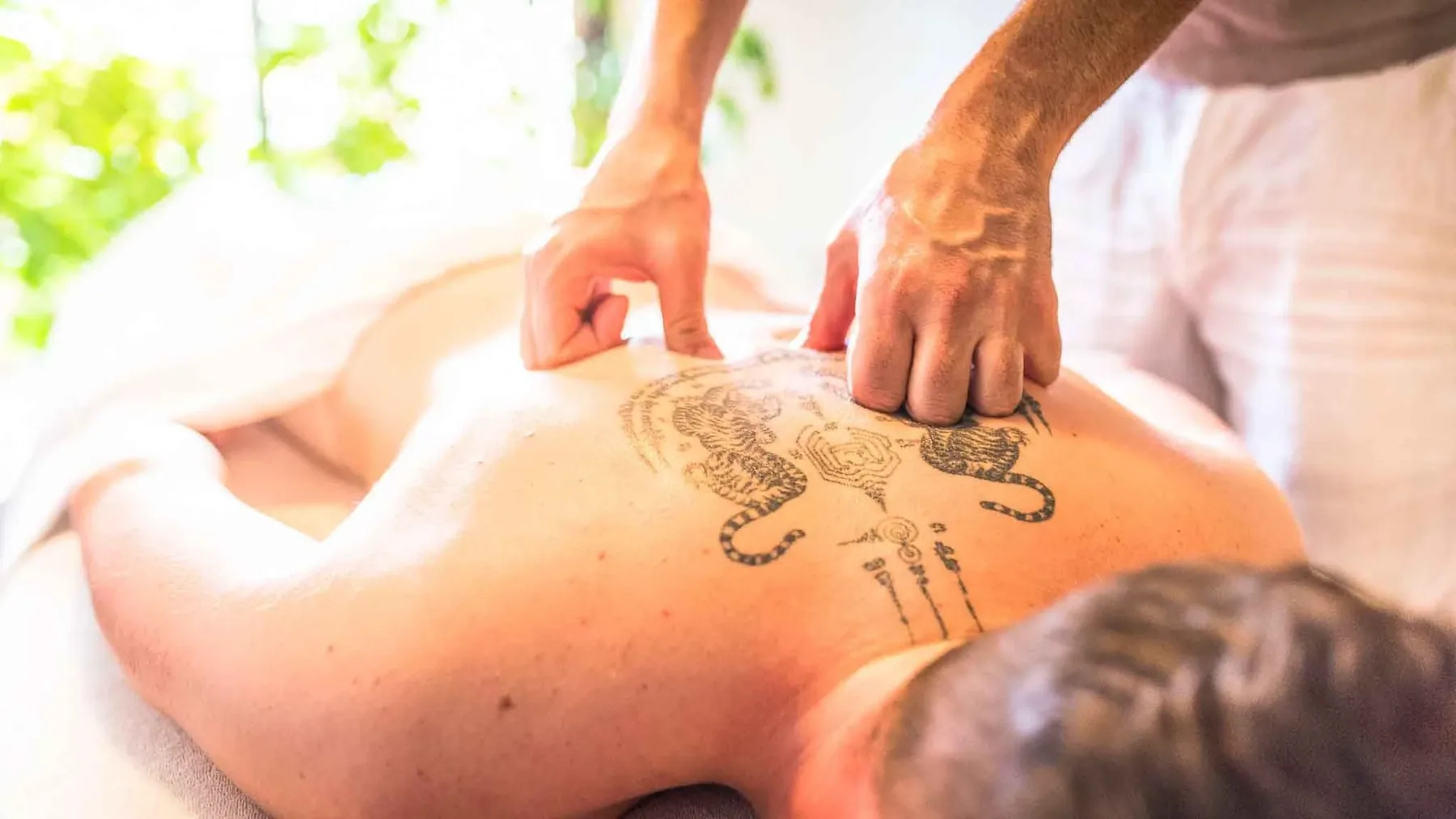 Un professionnel du massage à domicile à Nice en train d'exécuter un massage du dos sur un sportif de haut niveau